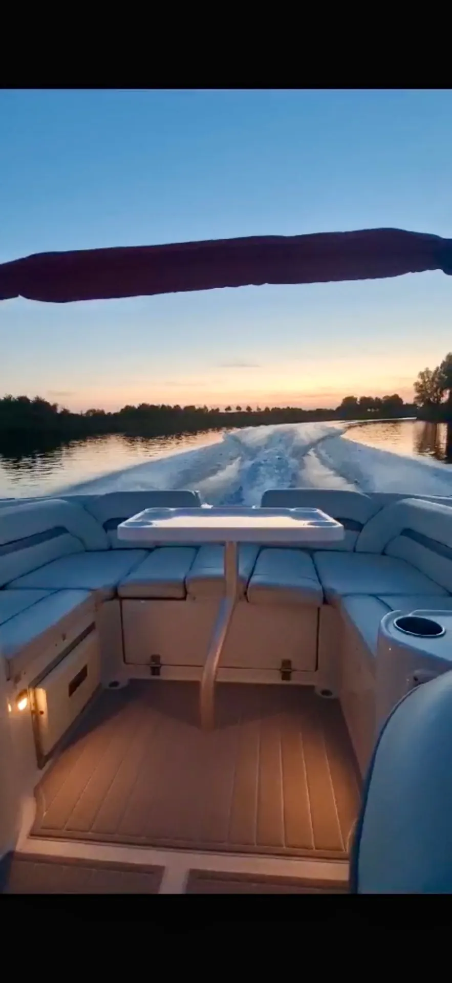 Zicht vanaf de achterbank op het kielzog bij zonsondergang
